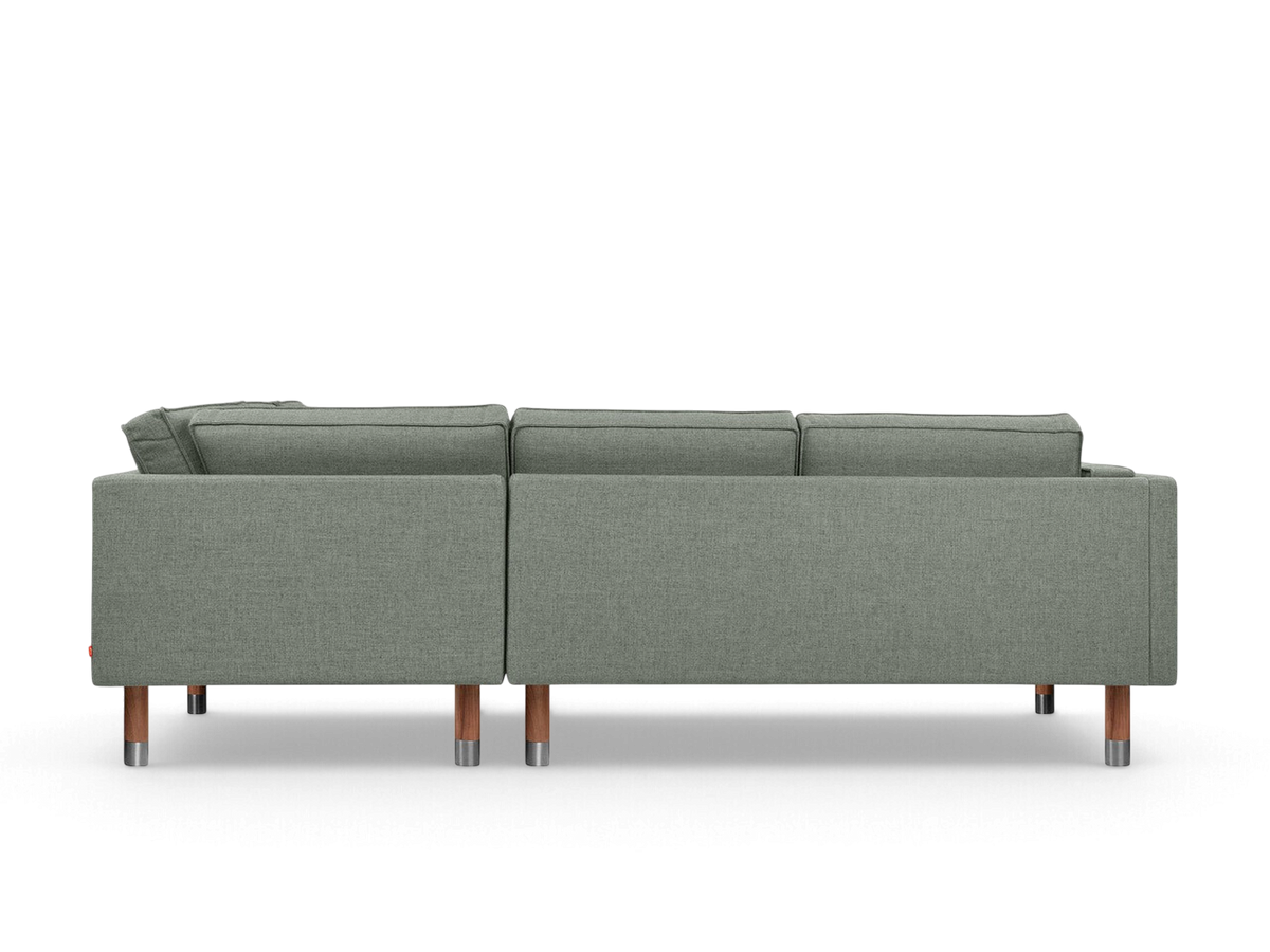 urbane EQ3 Augusta Bi-Sectional sofa in grey fabric with wooden legs and metal accents, viewed from the back.
