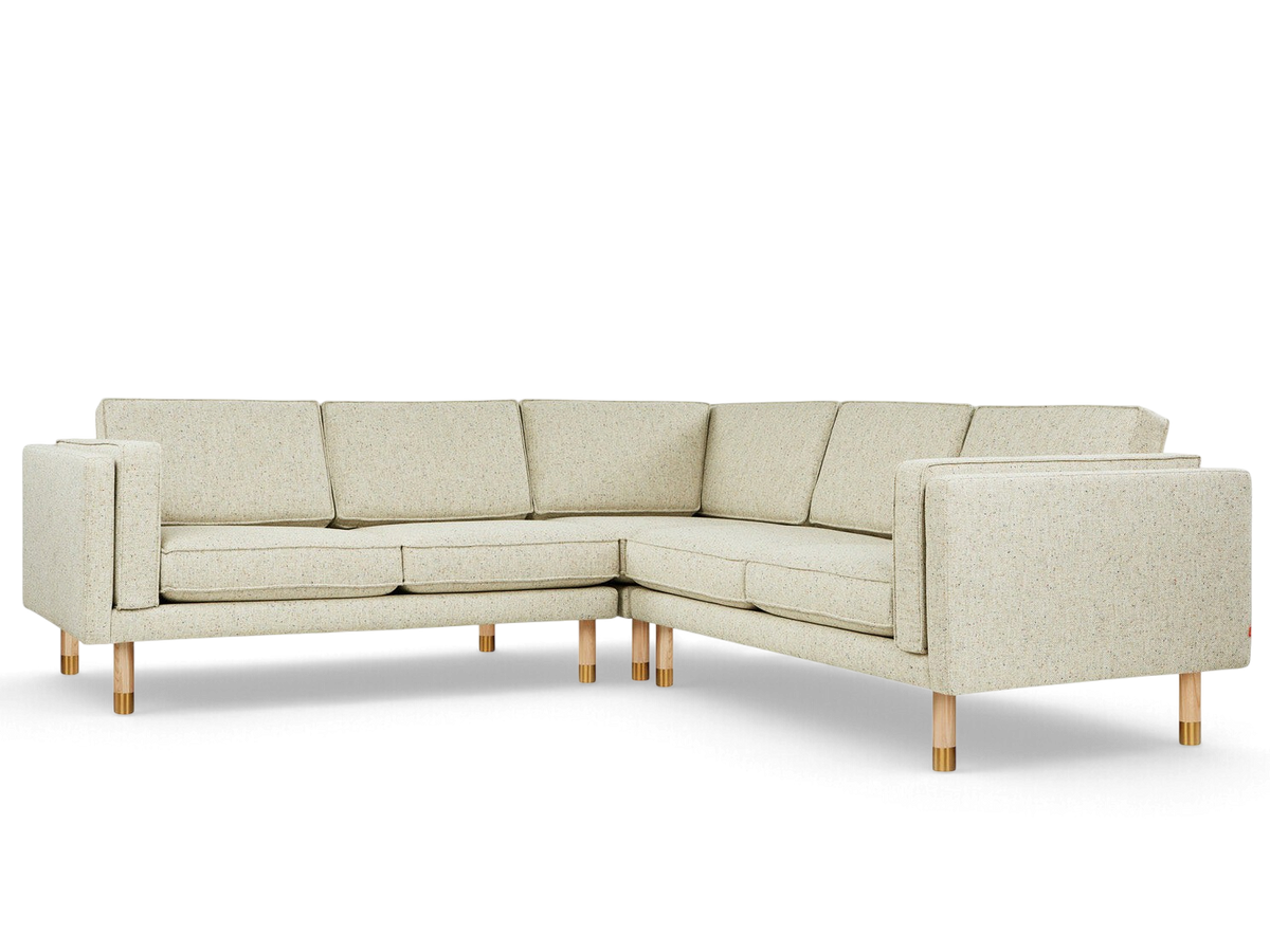 urbane EQ3 Augusta bi-sectional sofa in light textured fabric with natural ash and brass legs on a white background