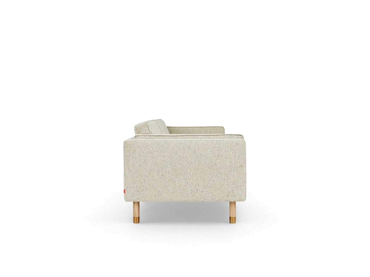 Side view of the urbane EQ3 Augusta 3-over-3 club sofa in light textured fabric with natural ash and brass legs.