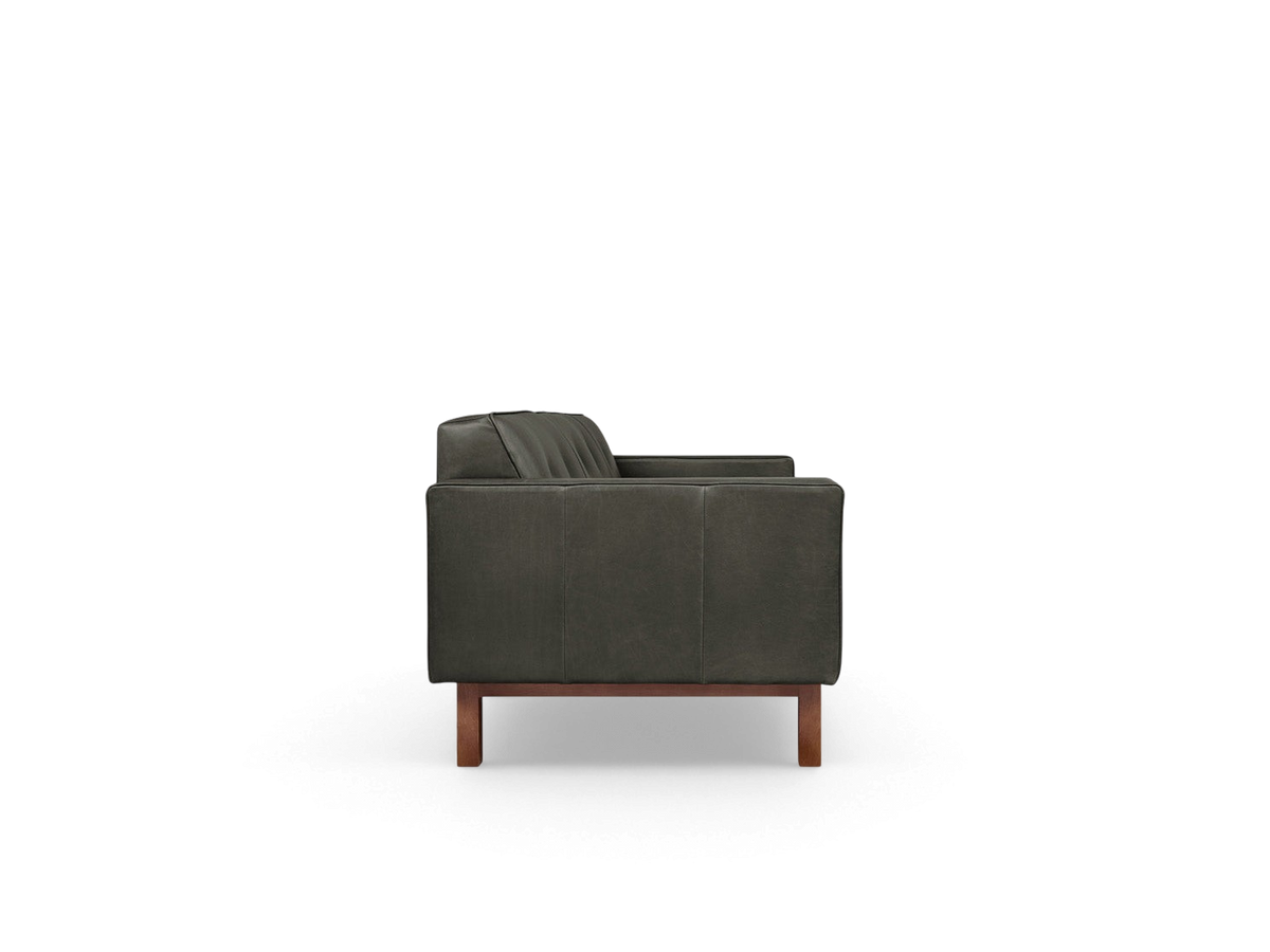 urbane EQ3 Embassy Sofa in dark leather with button-tufted back and walnut-stained wood base, side profile view