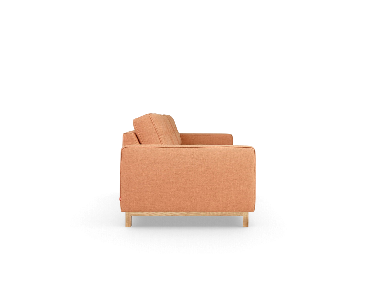Side view of the urbane EQ3 Jane 2 Sofa in a warm peach fabric with a natural ash wood base and button-tufted cushions.