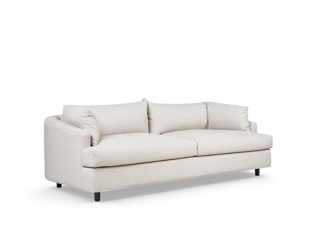 urbane EQ3 Thalia sofa in light beige fabric with a modern 1970s-inspired wraparound cushion design and black feet.