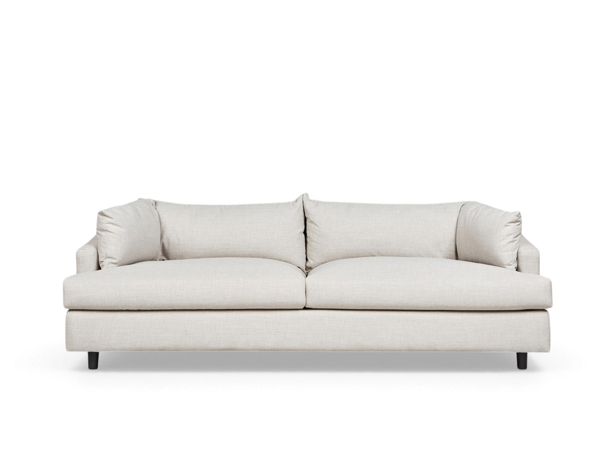 urbane EQ3 Thalia sofa in a neutral beige fabric with a 1970s-inspired wraparound cushion design and dark inset feet.