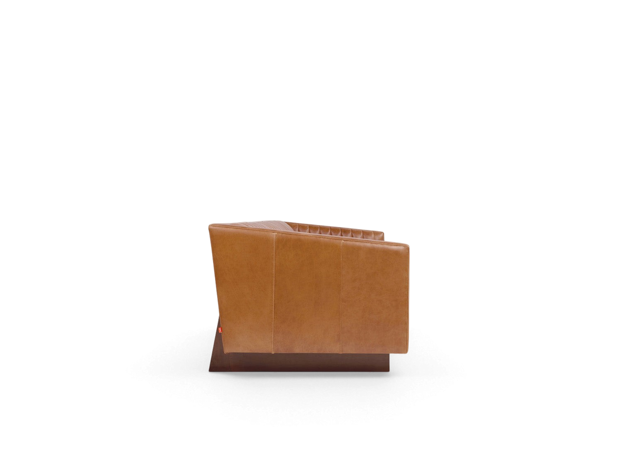 Side view of the urbane EQ3 Wallace Sofa in tan top grain leather with channel stitching and a walnut stained base.