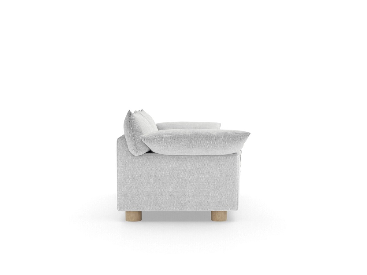 Side view of the urbane EQ3 Zoe sofa in light grey fabric with sculptural cushions and round oak legs.