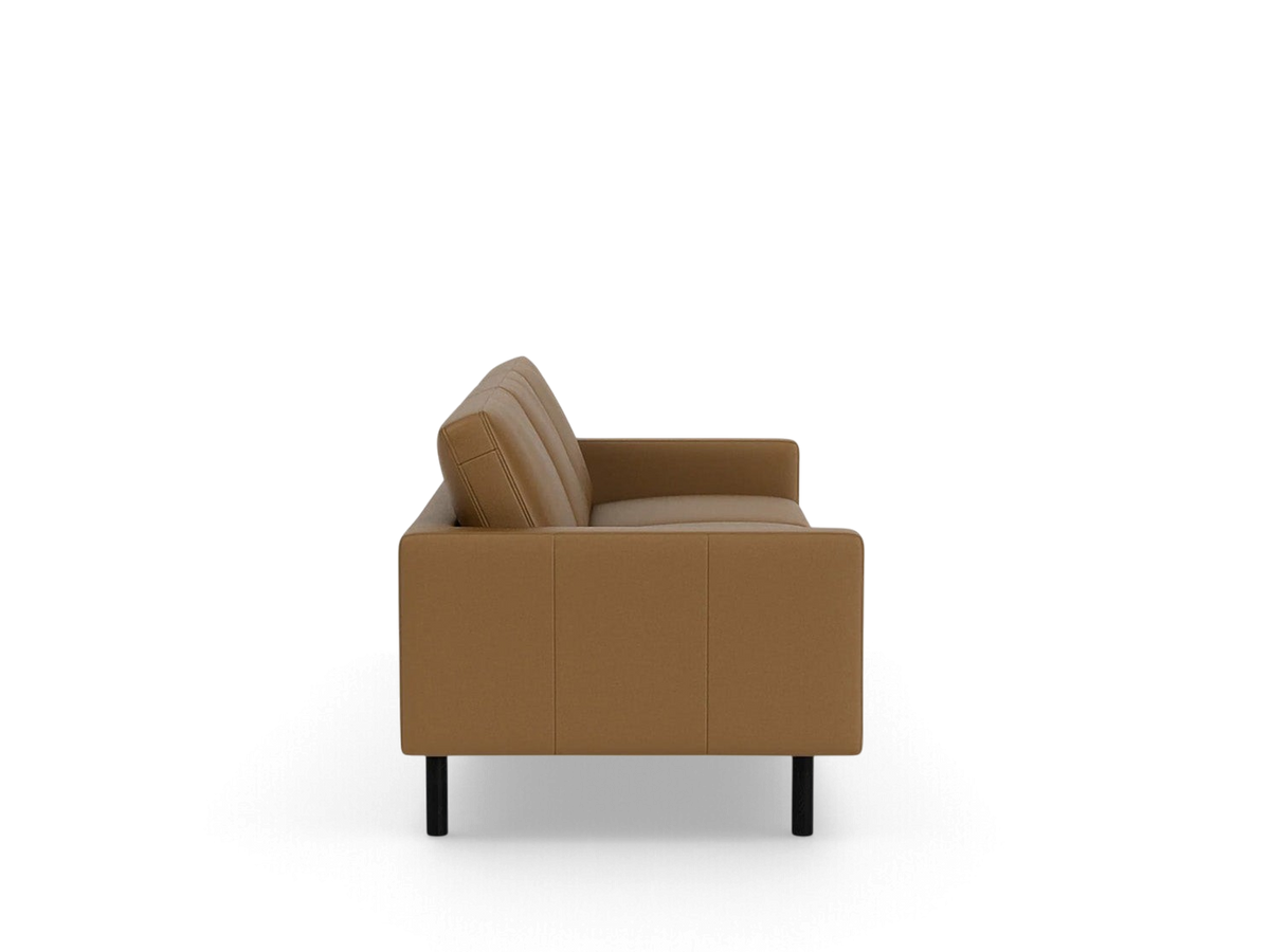 Side view of the mid-century inspired urbane EQ3 Joan 87-inch sofa in a warm tan fabric with black legs.