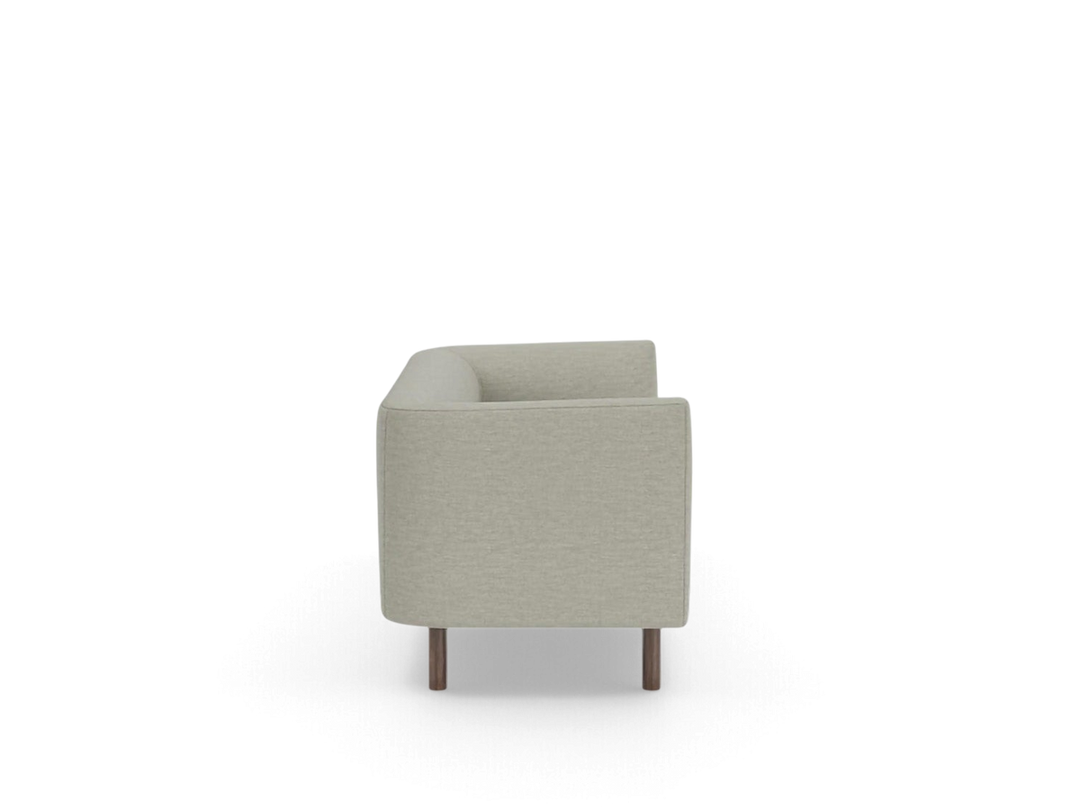 Side view of the urbane EQ3 Replay Club sofa in a light beige fabric with dark wooden legs